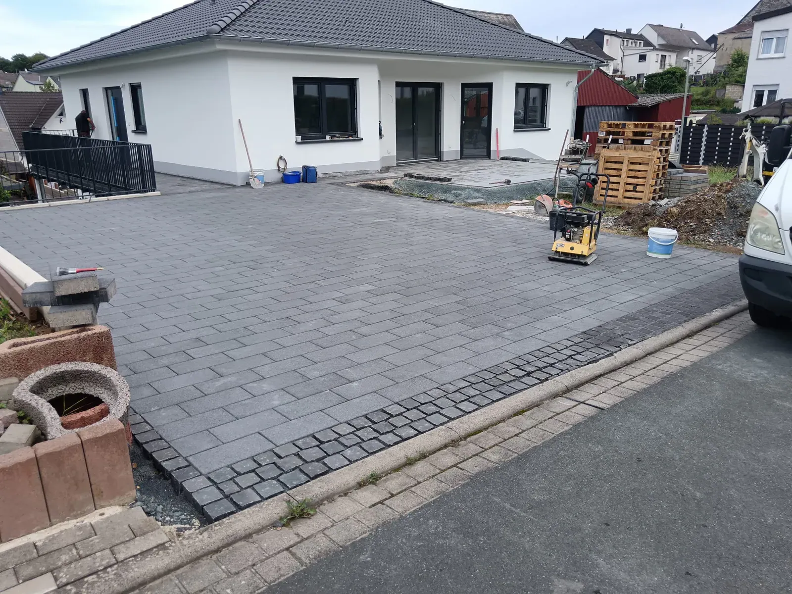 Weitläufig gepflasterte Zufahrt mit sauberem Übergang zur Terrasse und abgestimmtem grauem Pflasterbild.