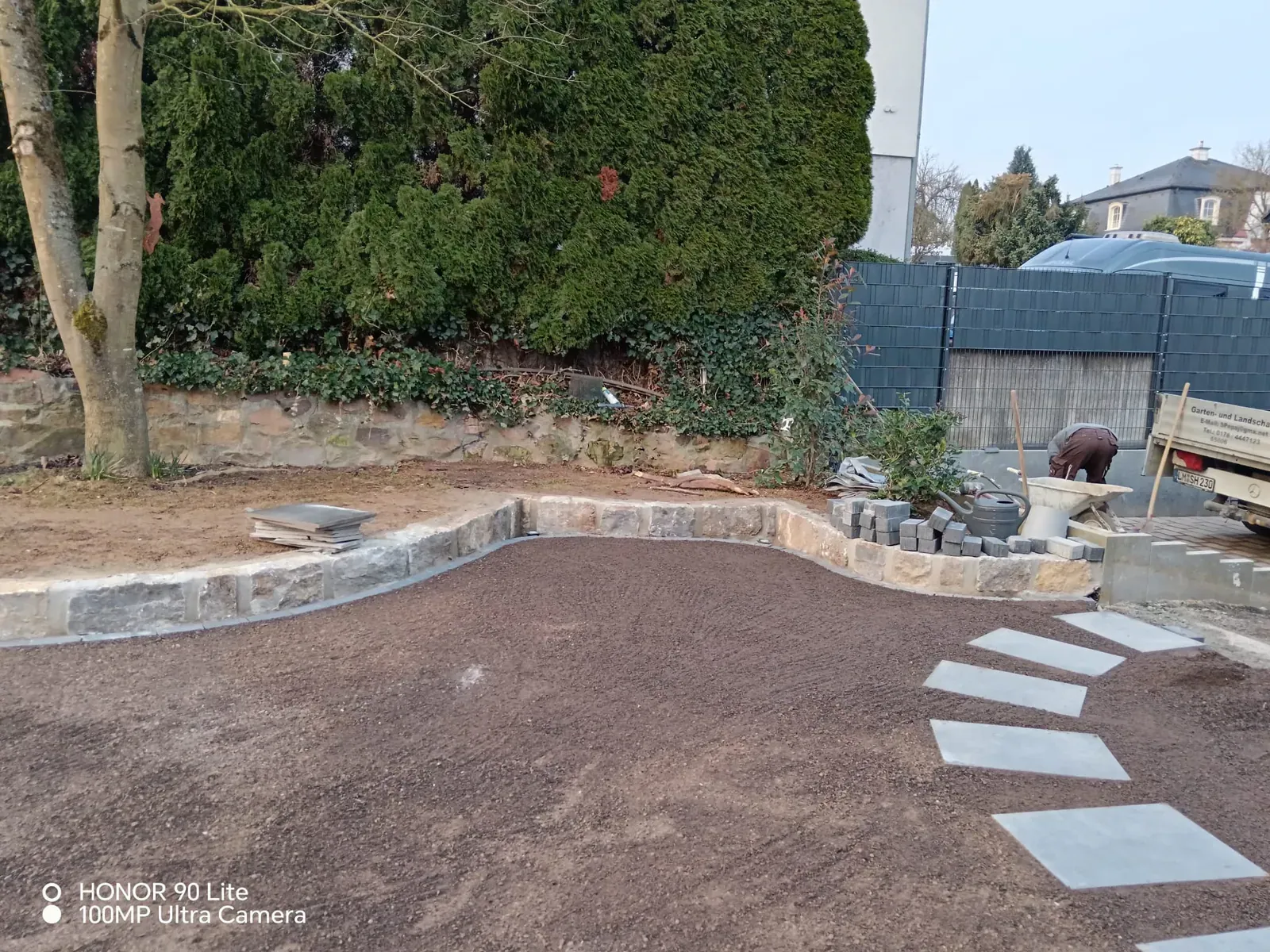 Vorbereitete Gartenfläche mit geschwungenen Beeteinfassungen, Trittplatten und kleiner Natursteinzone.