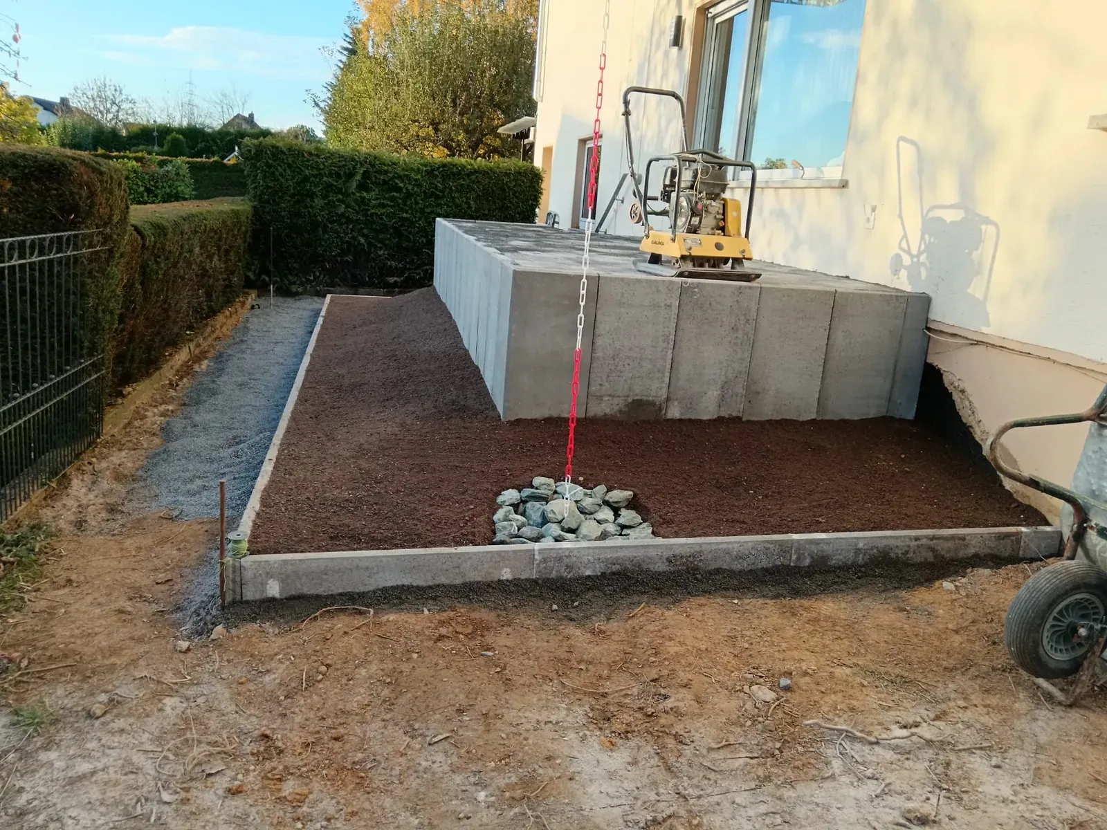 Rohbau einer Geländeterrassierung mit Betonstützwänden, Schotterunterbau und vorbereiteter Entwässerung.