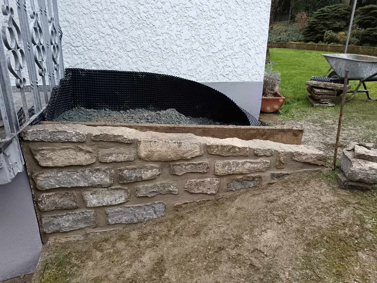 Individuell gemauerte Einfassung aus Naturstein mit handwerklich ausgearbeitetem Rundbogen.