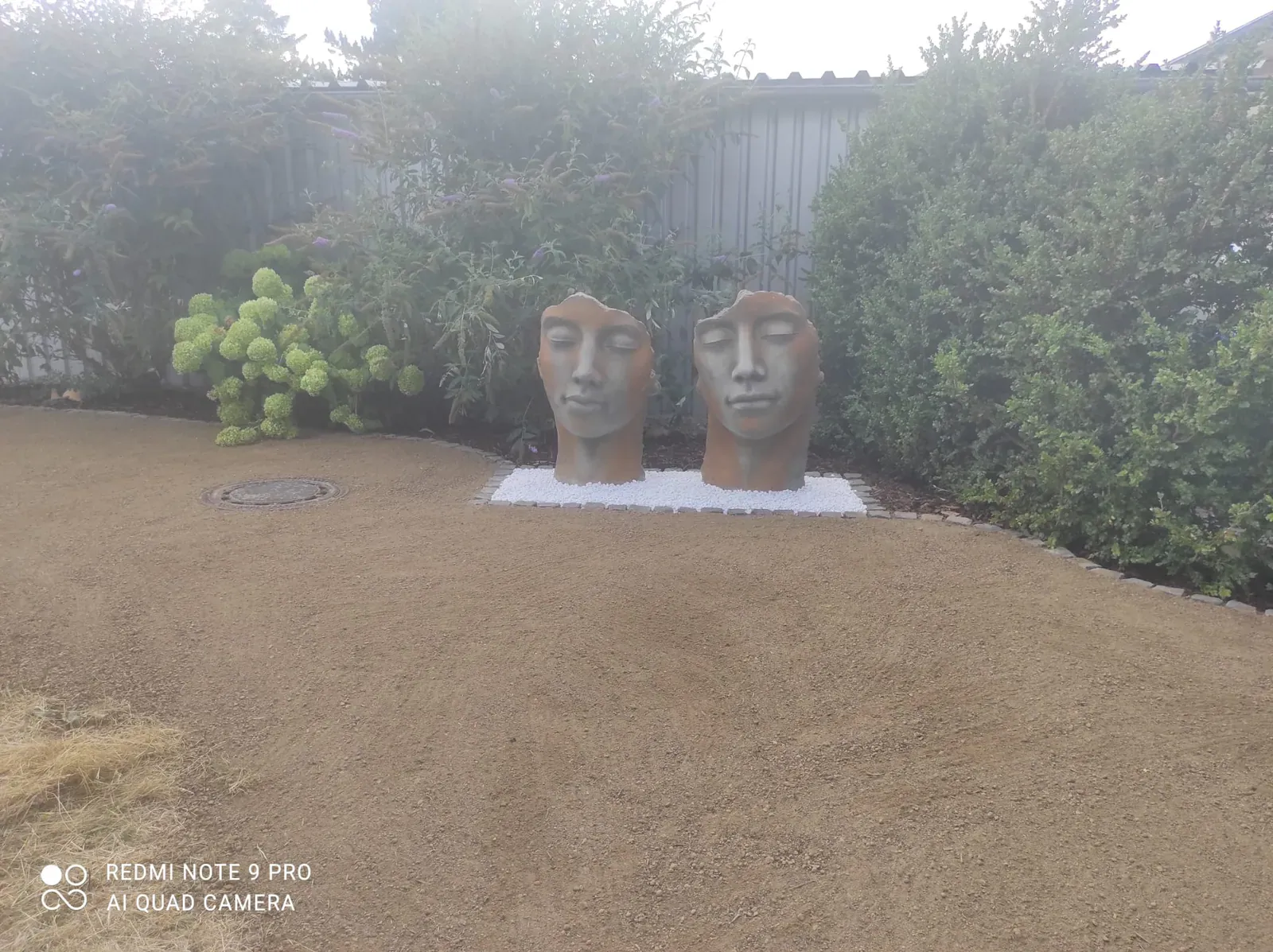 Fein vorbereitetes Rasenplanum rund um zwei markante Skulpturen und eine bestehende Hecke.