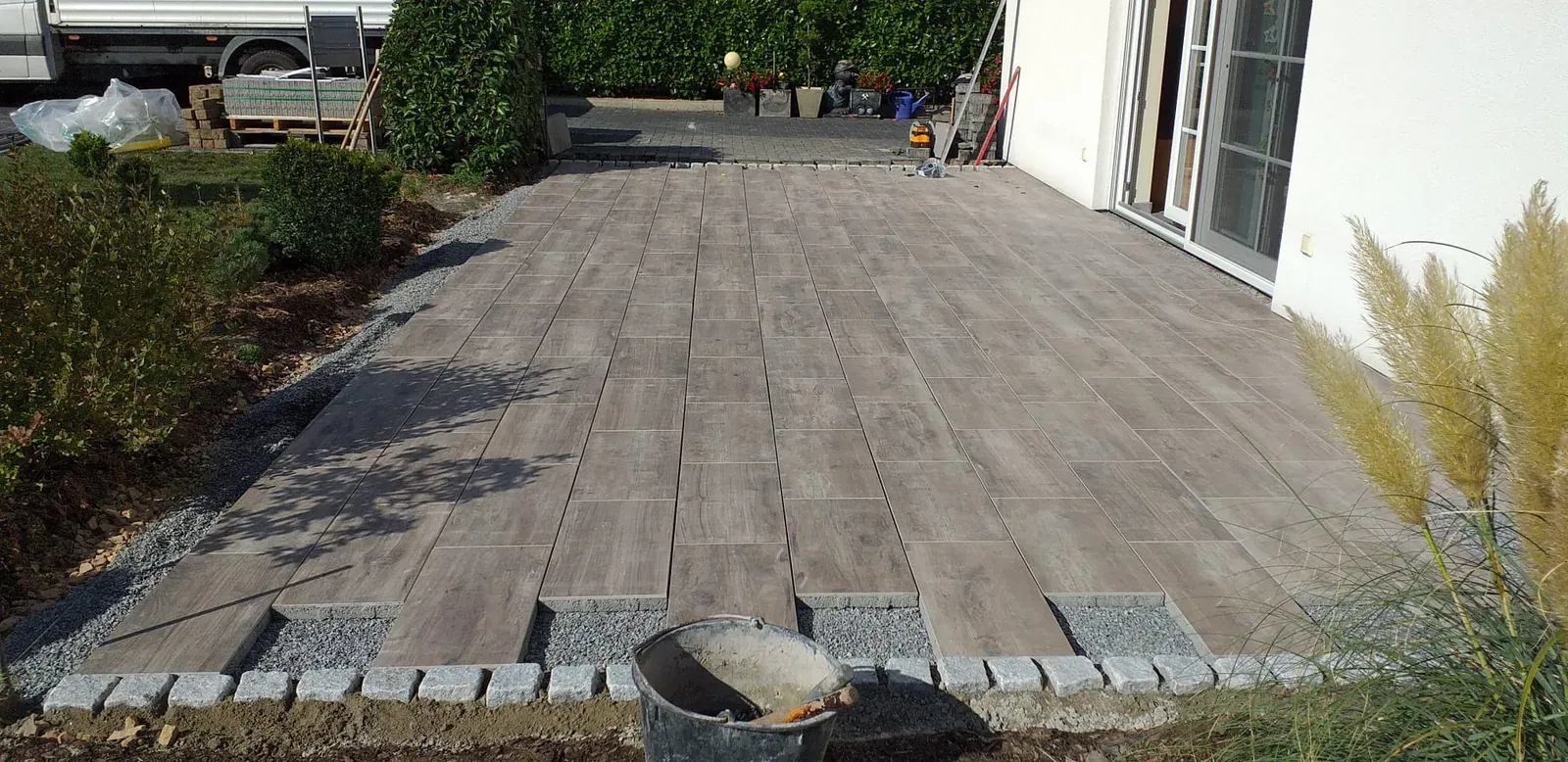 Große Terrassenfläche aus länglichen Platten mit warmer Holzmaserung und robustem Fugenbild.