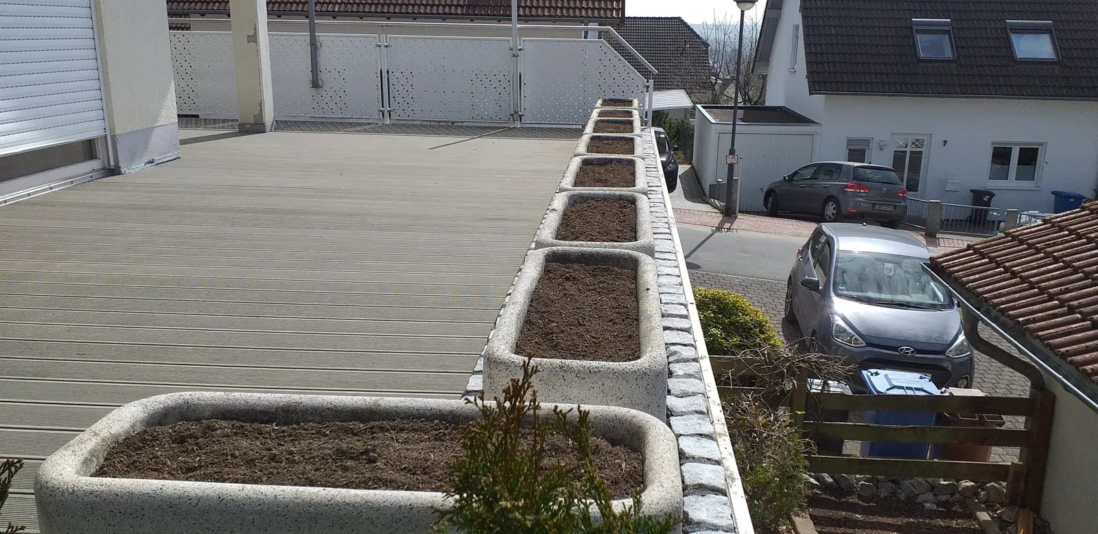 Panorama eines erhöhten Terrassenrands mit linear angeordneten Pflanztrögen und klarer moderner Gestaltung.