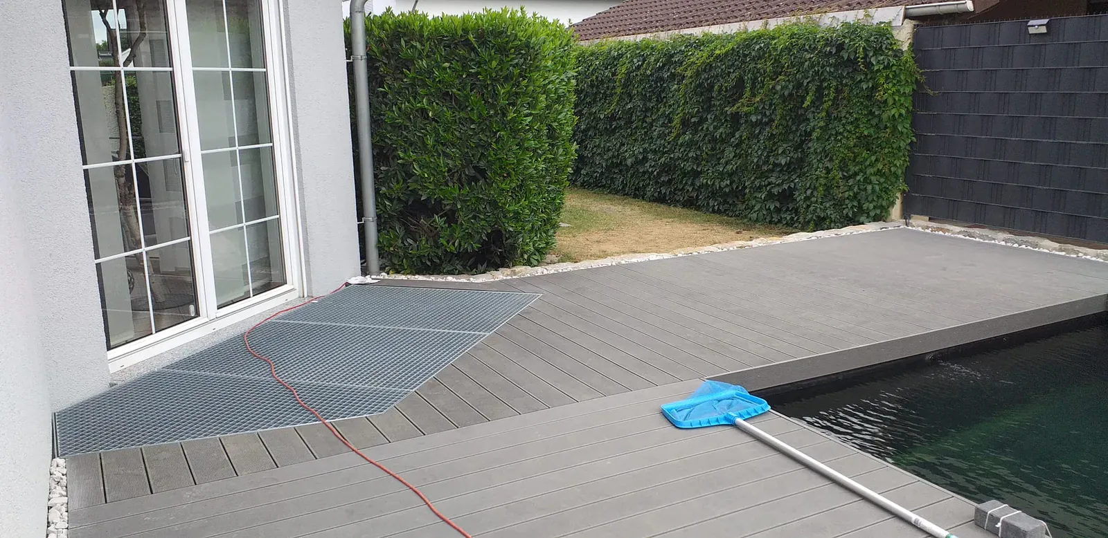 Pflegeleichte Terrassendielen in Holzoptik mit präzisem Anschluss an Pool, Rasen und Haus.